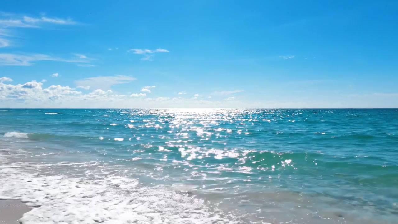 穏やかな海辺の情景：美しい日に穏やかな海の波と陽光が降り注ぐ海岸線を眺め、自然の息をのむような美しさと静けさを表現。