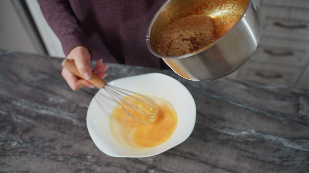 vista parcial de una persona moviendo la mezcla de huevos mientras vierte una sopa rica y sabrosa de la olla en el cuenco, las manos mezclando activamente los ingredientes en la encimera de mármol oscuro