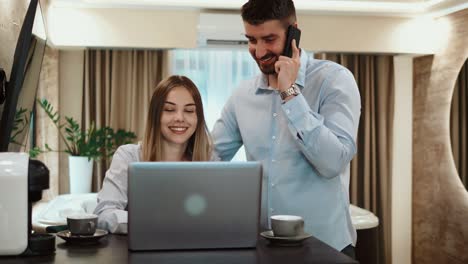 equipo de negocios con portátil y llamadas telefónicas en el hotel. joven gerente masculino hablando por teléfono mientras una hermosa joven mujer de negocios usando portátil en la habitación del hotel en un viaje de negocios