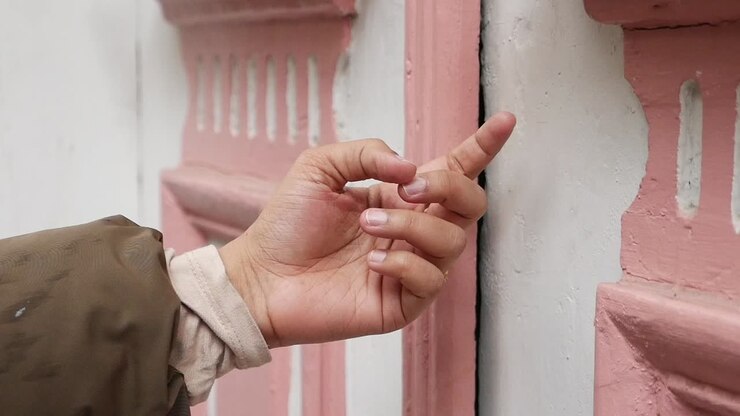 Hand touching a pink and white painted wall