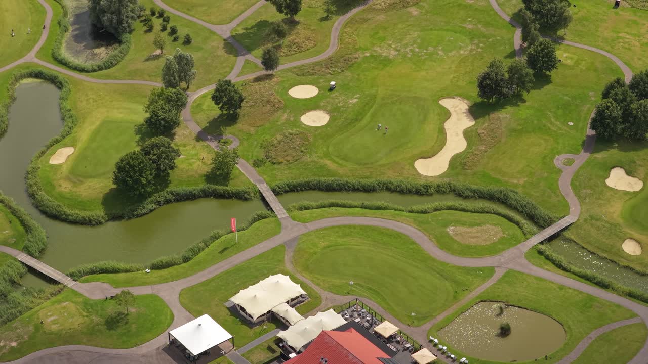 Green golf course in rural landscape, 18 holes with sand bunkers, aerial