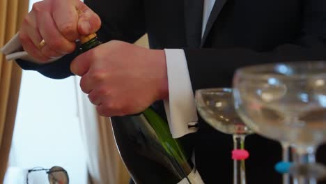 waiter pops open a bottle of sparkling wine at event with elegant glass display