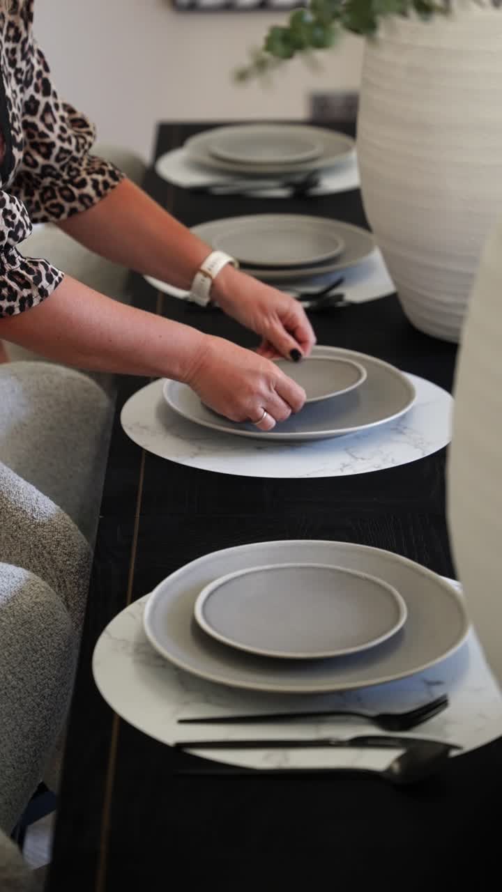 Una donna posiziona l'ultimo piatto sull'elegante tavolo da pranzo, creando un'atmosfera accogliente