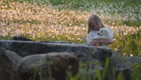 beautiful cute scene of blonde little girl holding puppy at park on a summer day