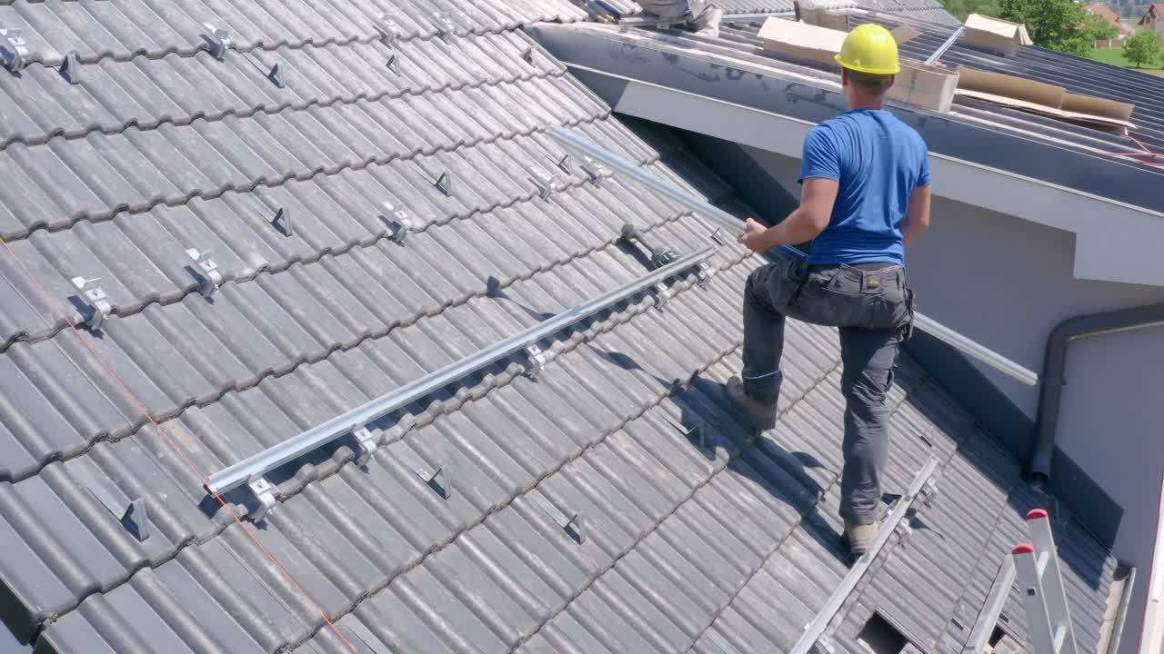 Adult Male Solar Installer Standing On Roof With Railing. Aerial View
