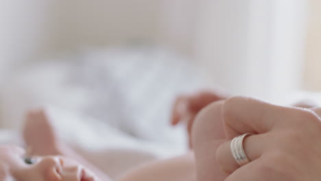 close up mother holding baby hand touching fingers nurturing newborn caring for infant enjoying motherhood connection with child