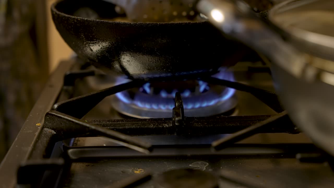 вид сбоку на голубое пламя газовой духовки или плиты, горящее под воком