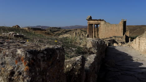 Ancient-Roman-ruins-in-Dougga-with-detailed-stone-textures-and-lichens,-under-clear-blue-sky