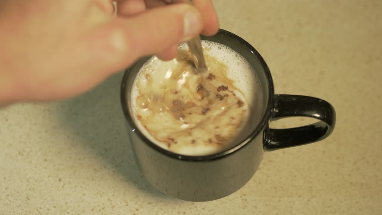 검은 머그잔에 핫초코 한 잔을 준비하는 사람의 오버헤드 샷