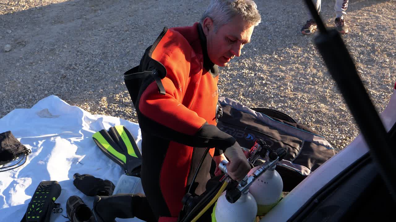 ripresa al rallentatore di un subacqueo che si gira e controlla le bombole di ossigeno prima dell'immersione
