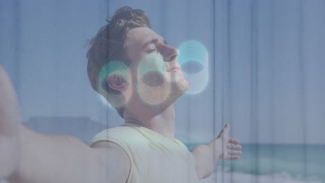 on beach, man with abstract circular animation overlay, relaxing by ocean waves