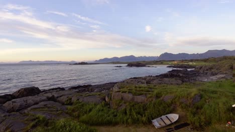 Antena-De-Una-Pequeña-Cabaña-Y-Barcos-En-La-Costa-De-Lofoten,-Noruega