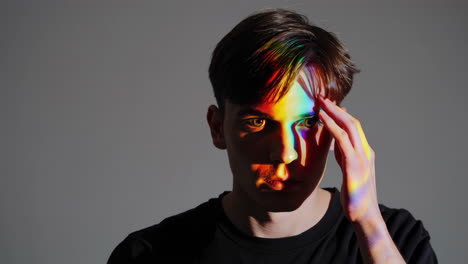 portrait of a young man with rainbow light on his face