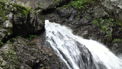 Una-Cascada-Poderosa-Y-Fuerte-Con-Muchas-Rocas-Alrededor,-Con-Algo-De-Vegetación-Verde