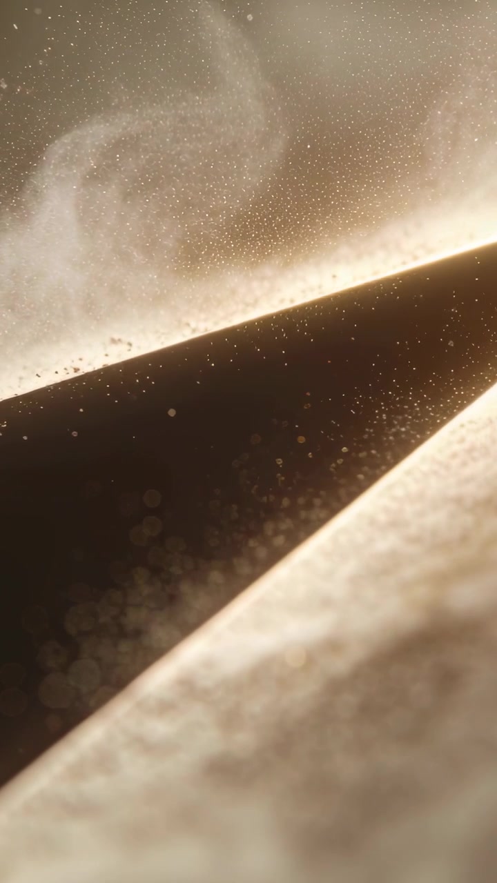 Vertical video: Catching rim light, sloped gap showing rising dust plume in macro, bokeh floating