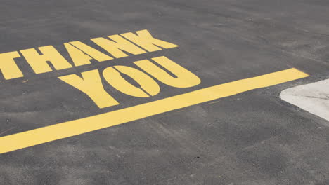 thank you message painted in yellow on asphalt parking lot surface camera pan tilt