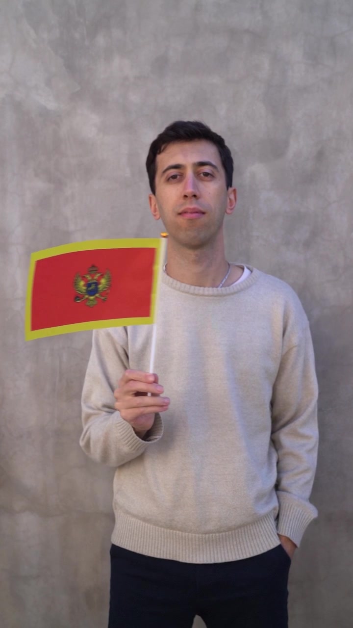 Vertikalaufnahme einer Person, die die montenegrinische Flagge in Zeitlupe schwenkt. Landesflagge Montenegros