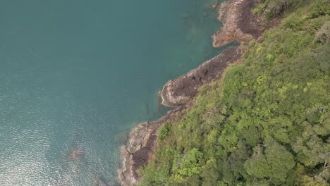 antena, vista de pájaro dolly spin tiro giratorio de la costa oceánica de granito rocoso tropical con exuberante vegetación de bosque tropical en una isla en tailandia