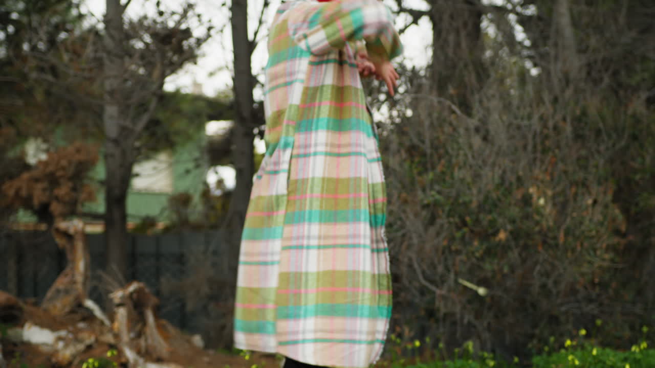 Woman In Plaid Shirt Slowly Dances In Front Of Trees In Park