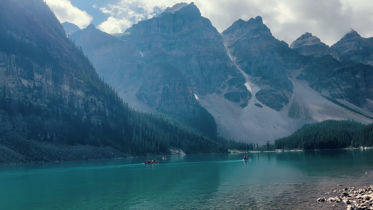 Boats gliding over the crystal-clear blue-green waters of Moraine Lake, nestled in the heart of Banff, Canada.