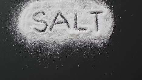 Animation-of-salt-text-written-in-salt-on-black-background