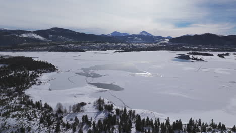 downtown frisco toward keystone colorado aerial cinematic drone lake dillon marina summit cove cloudy snowy winter morning view silverthorne ten mile range breckenridge calm unfrozen ice circle left