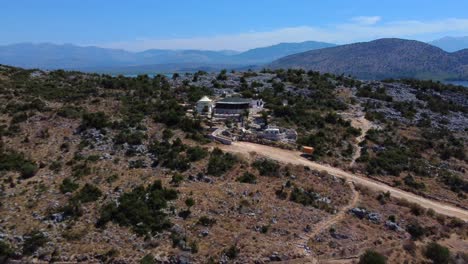 Drone-shot-of-a-restaurant-located-on-top-of-a-hill-in-Ksamil,-Albania---drone-is-reversing