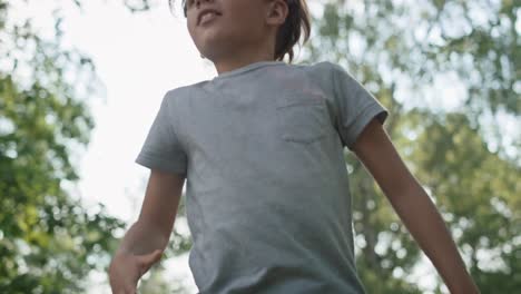 un niño caucásico saltando en el trampolín en el patio de recreo.
