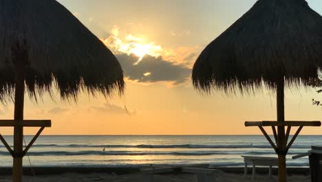 puesta de sol bali indonesia, 2 sombrillas tiki en la playa
