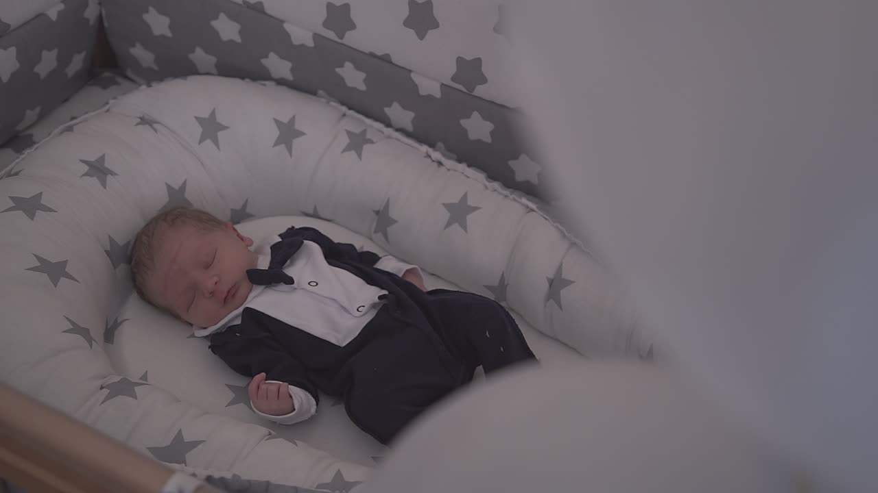 un bambino carino in uno smoking divertente dorme in una comoda culla a casa