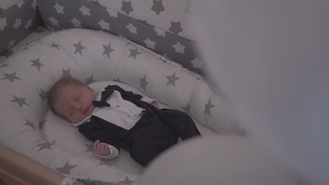 cute baby in funny tuxedo sleeps in comfortable cot at home