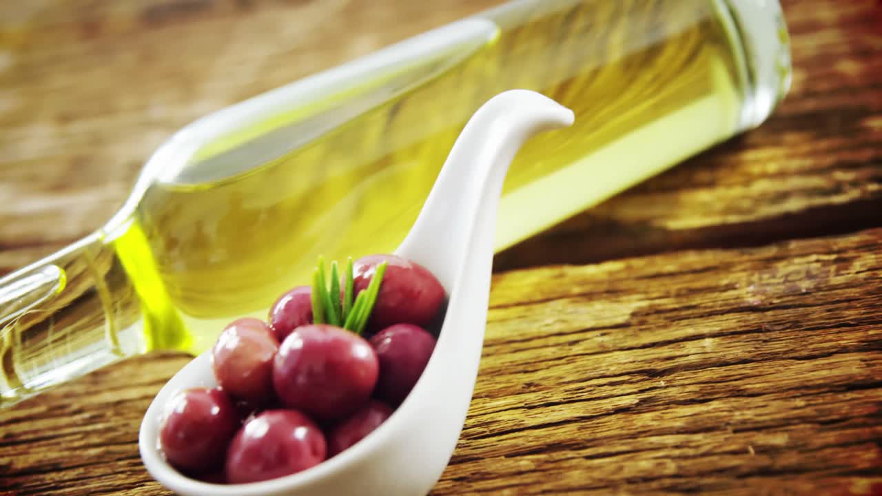 Olive oil bottle and spoon full of red olives