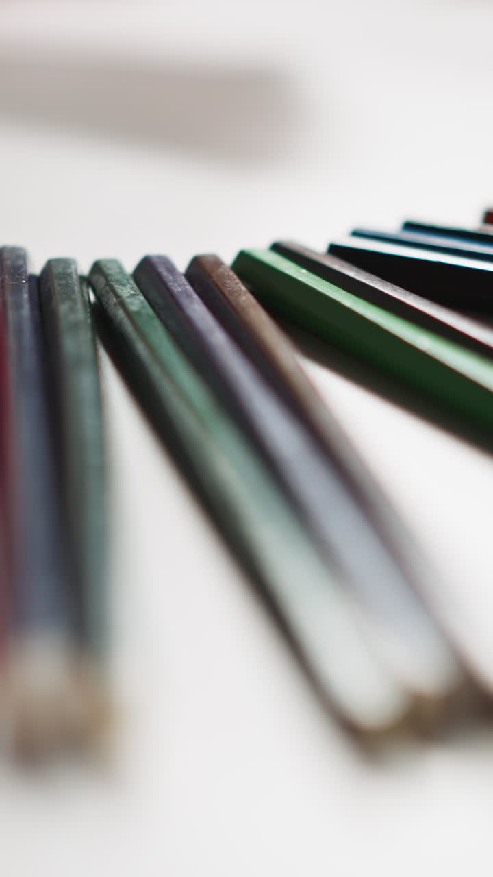 Hand of little girl takes bright yellow pencil to draw picture on white paper sheet at art lesson in classroom close view slow motion