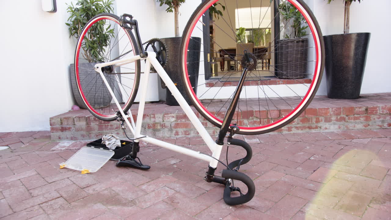 Repairing bicycle, tools on ground, bike upside down in front of house, at home