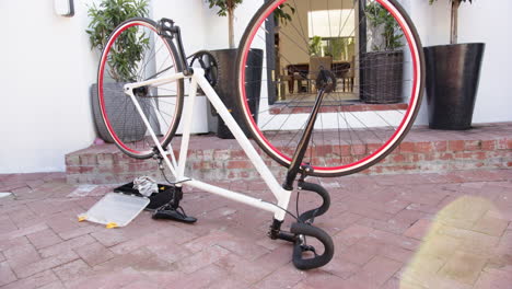 repairing bicycle, tools on ground, bike upside down in front of house, at home
