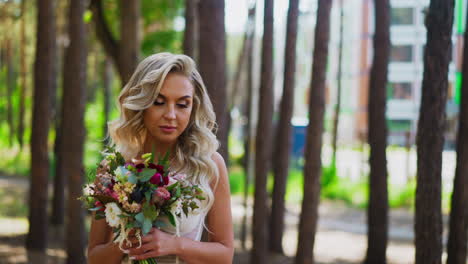 Languid-bride-with-hairstyle-holds-flowers-bouquet-in-park