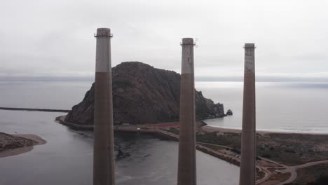 Aerial-close-up-reverse-pullback-shot-of-the-famous-three-smokestacks-above-the-abandoned-Morro-Bay-Power-Plant-in-Morro-Bay,-California