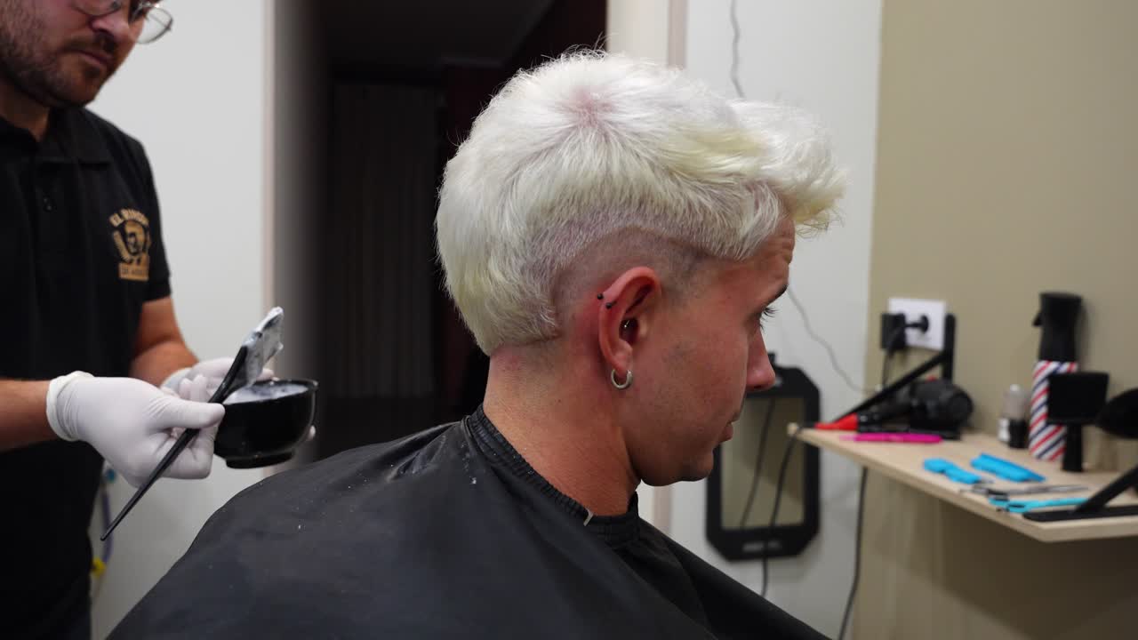 Profile shot of a man receiving a third bleaching application as hair colour shifts toward white