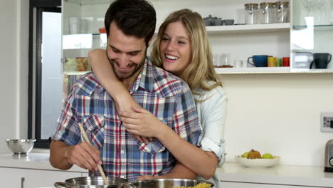 chica linda abrazando a su novio mientras él está cocinando