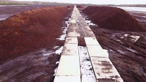 aerial dolly out revealing a long peat deposit mining site in plain forest landscape