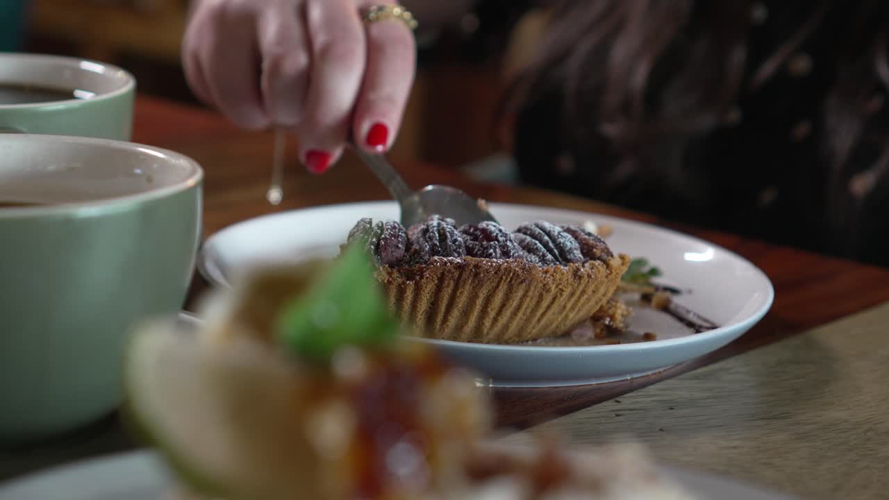 Woman eats a dessert and drinks coffee in a cafe, women hands eating pie dessert with a spoon