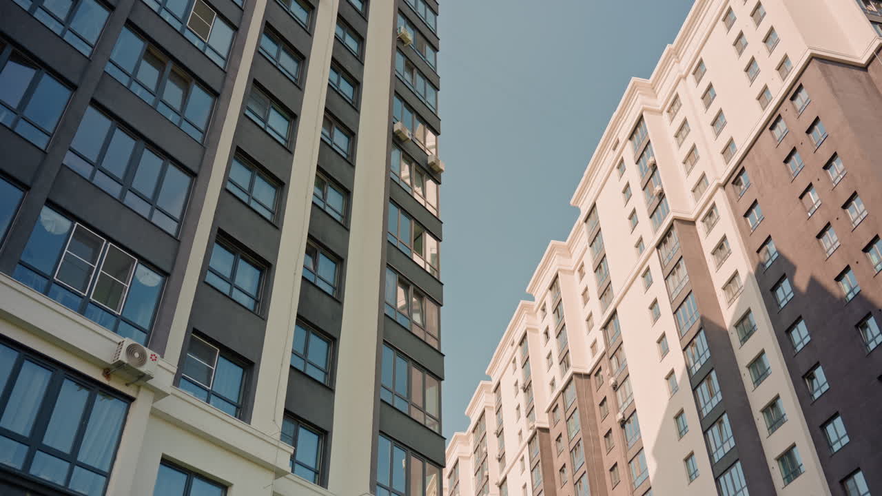 Looking Up At Glass Skyscraper Towers With Clear Blue Sky, Modern Brick And Concrete Facades, Reflective Windows, Sharp Vertical Lines And Warm Sunlight, Calm Urban Ambience Ideal For Architecture