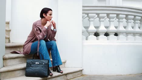 fashion conscious young woman sitting on steps of city building