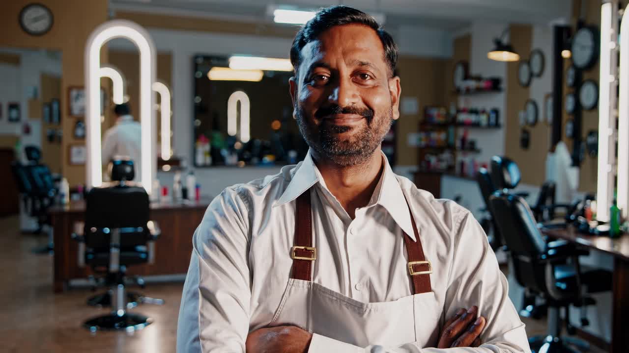 A mid-shot video captures a smiling barber in a modern barbershop, with a focus on the stylish