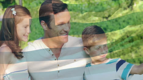 animation of flag of greece over caucasian father with children taking photo in park