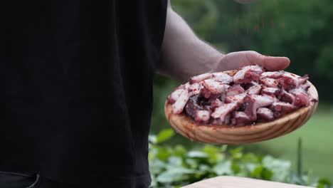 detail of a man preparing an octopus tapa, adding pepper and olive oil