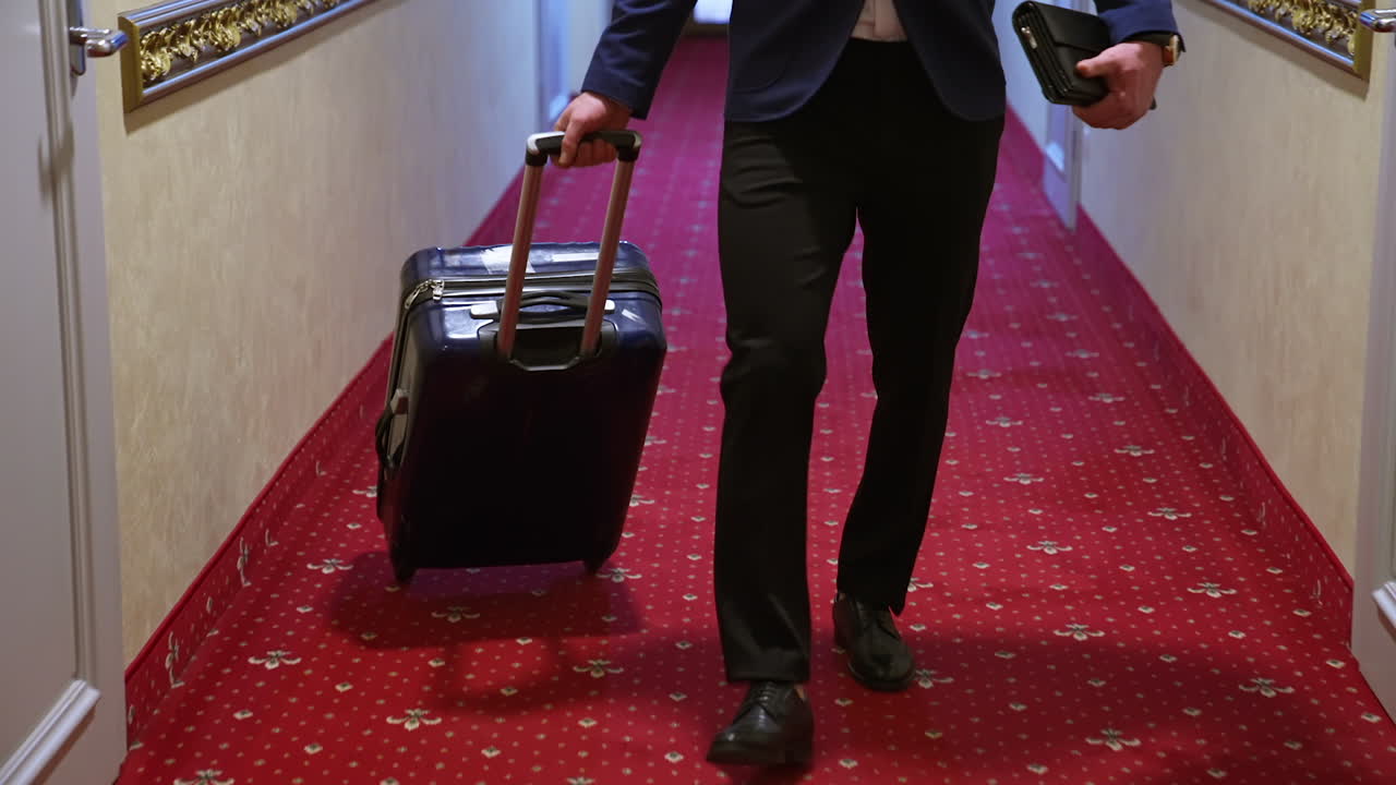 Businessman in hotel corridor with suitcase. Male businessman walking with luggage in hotel corridor