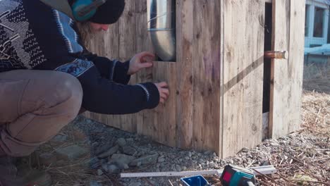 el hombre está comprimiendo una sección para insertar la tabla de madera en la bañera de agua caliente casera - de cerca