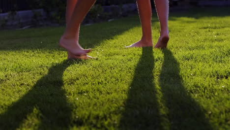 two barefoot women run on the green grass in jets of water. youth and health concept