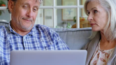 Senior-couple-using-laptop-on-sofa-4k